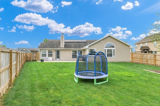 4022 Orchard Ln, Monticello, IL 61856 - rear view of house with a trampoline, a chimney, solar panels, and a patio area