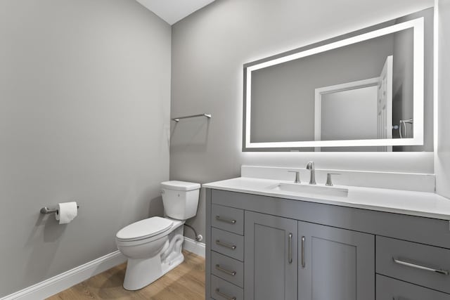 bathroom featuring baseboards, vanity, toilet, and wood finished floors
