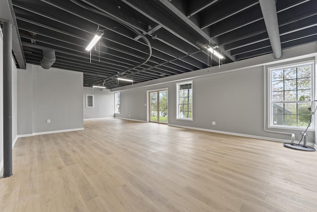 unfurnished living room with baseboards and light wood-type flooring