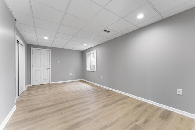 empty room with visible vents, light wood finished floors, and a drop ceiling