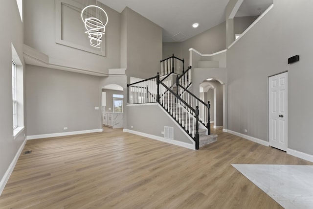 entryway featuring visible vents, a towering ceiling, baseboards, stairway, and arched walkways