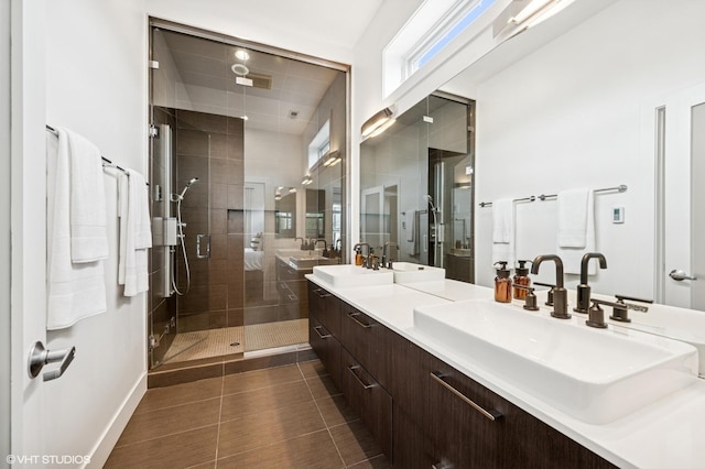 bathroom with a shower stall, double vanity, tile patterned floors, and baseboards
