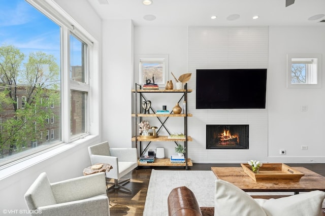 living room featuring plenty of natural light, wood finished floors, a large fireplace, and recessed lighting