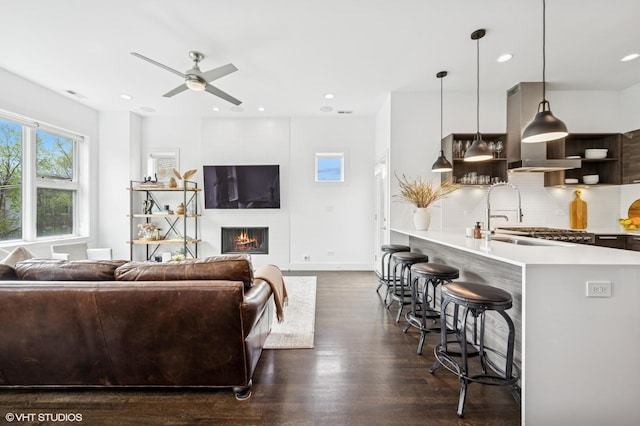 living area featuring ceiling fan, dark wood-style floors, a large fireplace, recessed lighting, and baseboards
