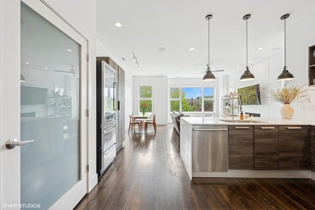 kitchen with stainless steel appliances, a sink, dark wood finished floors, light countertops, and modern cabinets