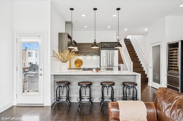 bar featuring dark wood-style flooring, tasteful backsplash, stairs, built in refrigerator, and recessed lighting