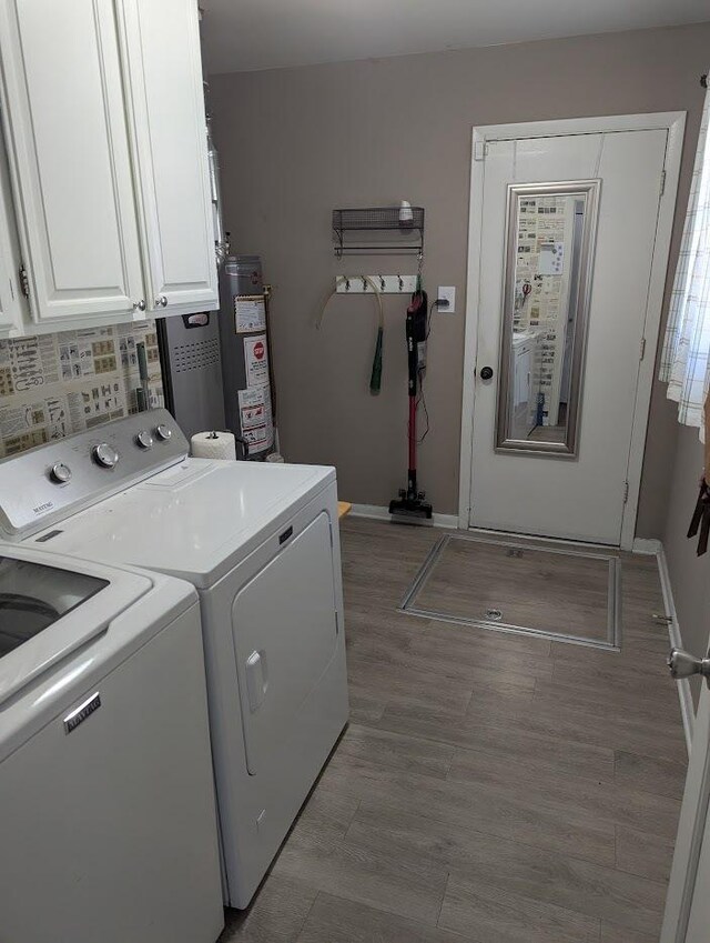 laundry area with cabinet space, light wood-style floors, water heater, baseboards, and washing machine and dryer