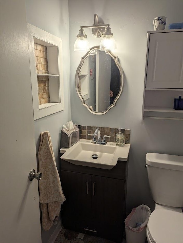 half bathroom featuring toilet, tasteful backsplash, and vanity