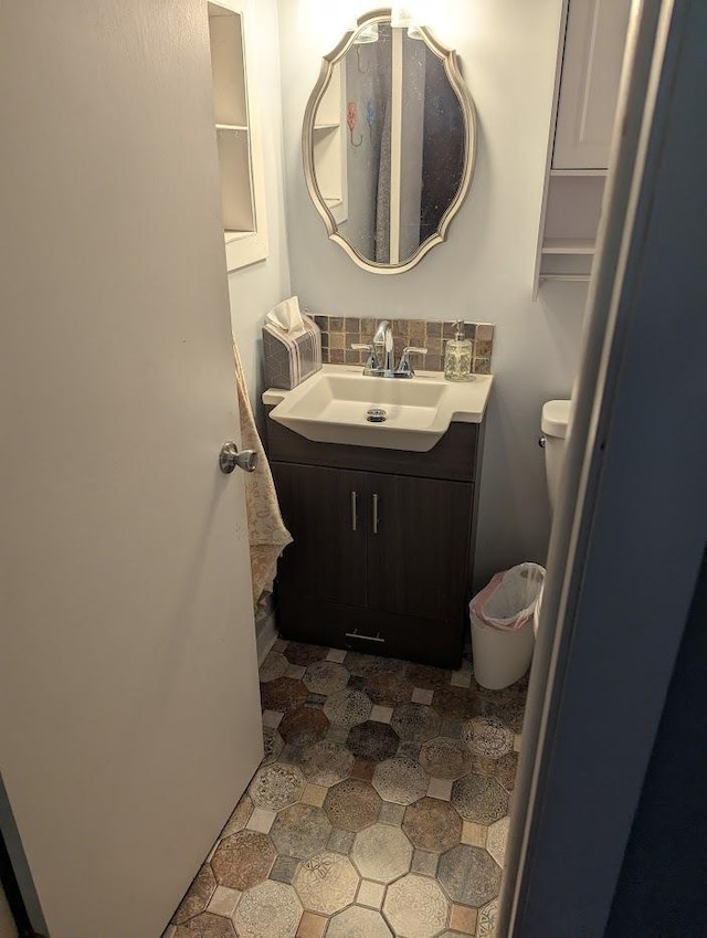 half bathroom featuring vanity, tile patterned floors, backsplash, and toilet