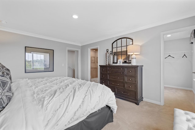 bedroom featuring a walk in closet, baseboards, a closet, ornamental molding, and light carpet