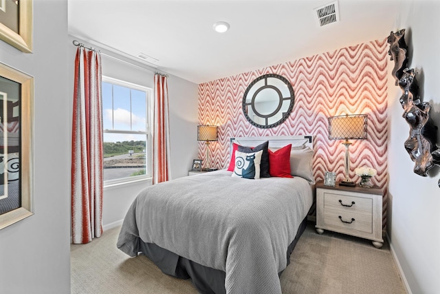 bedroom with an accent wall, baseboards, visible vents, and carpet