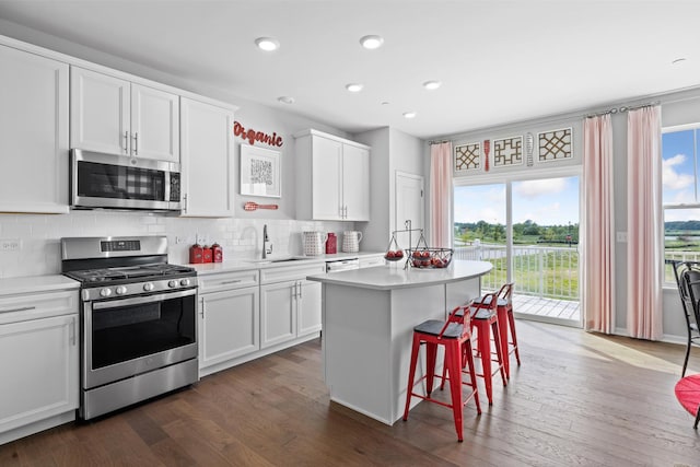 kitchen with decorative backsplash, a kitchen island, appliances with stainless steel finishes, a sink, and light countertops