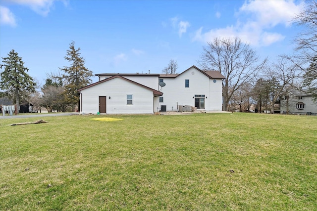 rear view of property with a yard and central air condition unit