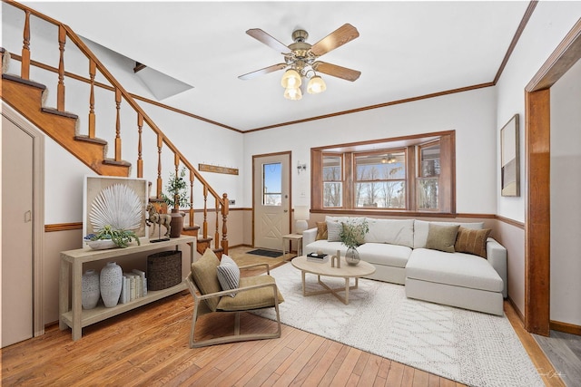 living room featuring wood-type flooring, a ceiling fan, stairway, and ornamental molding
