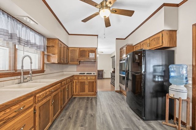kitchen featuring a sink, ornamental molding, freestanding refrigerator, and brown cabinets