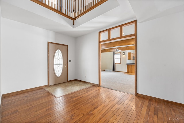 entryway featuring baseboards, a towering ceiling, and hardwood / wood-style floors