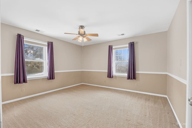 spare room featuring carpet floors, ceiling fan, visible vents, and baseboards