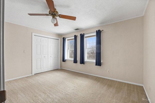 unfurnished bedroom featuring carpet flooring, a ceiling fan, baseboards, visible vents, and a closet