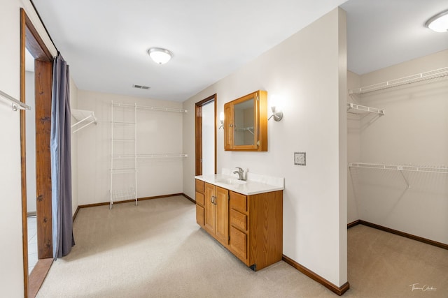 full bath featuring carpet floors, baseboards, a walk in closet, and vanity