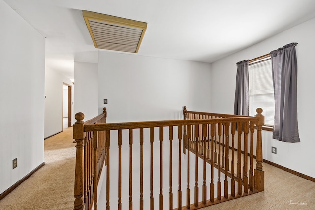 hall featuring baseboards, light carpet, and an upstairs landing