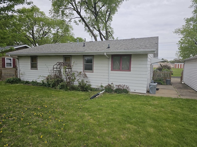 back of property with a yard, fence, and roof with shingles