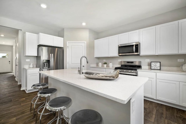 kitchen with stainless steel appliances, dark wood finished floors, a kitchen breakfast bar, and recessed lighting