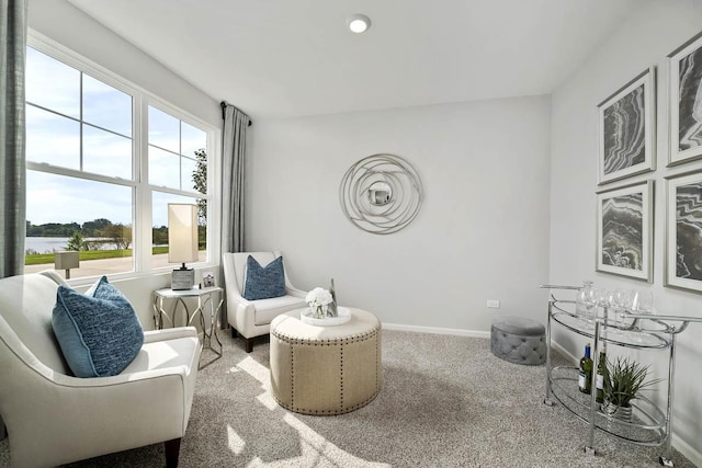 living area featuring carpet flooring, a water view, and baseboards
