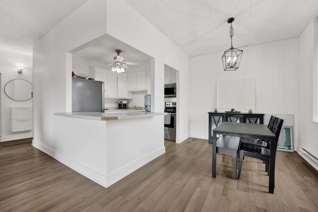 kitchen featuring light countertops, appliances with stainless steel finishes, a peninsula, and wood finished floors