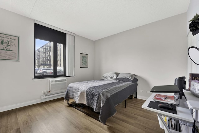 bedroom with baseboards, baseboard heating, and wood finished floors