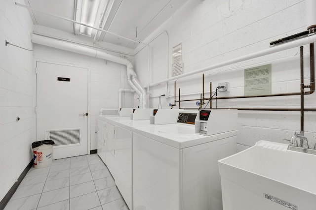 common laundry area featuring a sink, concrete block wall, visible vents, and washer and dryer
