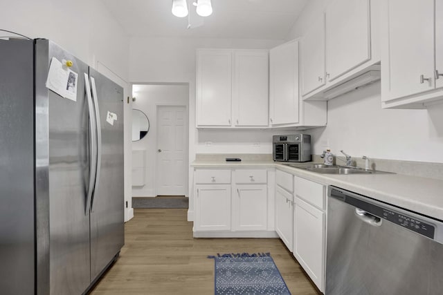 kitchen with a sink, white cabinetry, appliances with stainless steel finishes, and light countertops