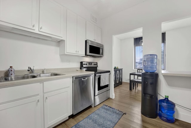 kitchen featuring visible vents, white cabinets, a sink, light wood finished floors, and stainless steel appliances