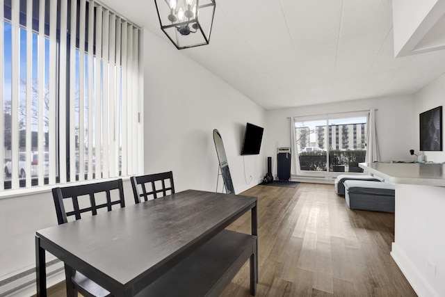 dining area featuring an inviting chandelier, baseboards, baseboard heating, and wood finished floors