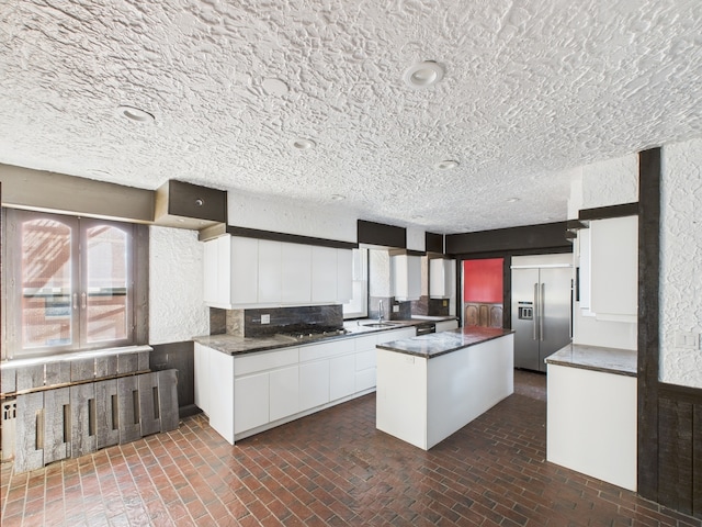 5555 S Everett Ave Unit B3-4, Chicago, IL 60637 - kitchen featuring a center island, a sink, dark countertops, stainless steel appliances, and white cabinetry