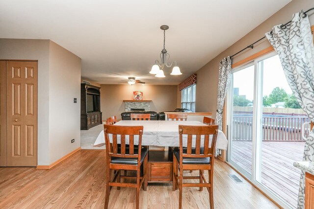 1678 Eagles Lndg N, Manteno, IL 60950 - dining area featuring light wood-type flooring, a stone fireplace, ceiling fan, and a chandelier