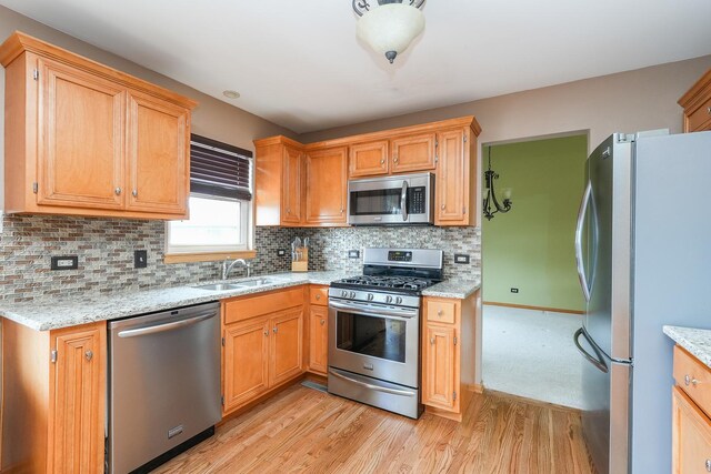 1678 Eagles Lndg N, Manteno, IL 60950 - kitchen featuring appliances with stainless steel finishes, light wood-type flooring, a sink, light stone counters, and tasteful backsplash