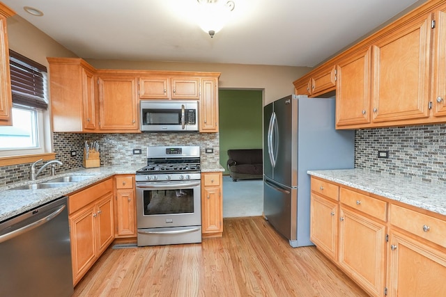 1678 Eagles Lndg N, Manteno, IL 60950 - kitchen featuring appliances with stainless steel finishes, a sink, light wood-style floors, decorative backsplash, and light stone counters