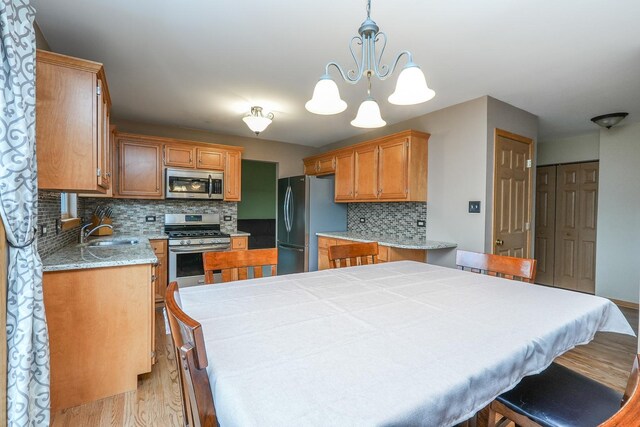 1678 Eagles Lndg N, Manteno, IL 60950 - kitchen with stainless steel appliances, light wood finished floors, a sink, decorative backsplash, and light countertops