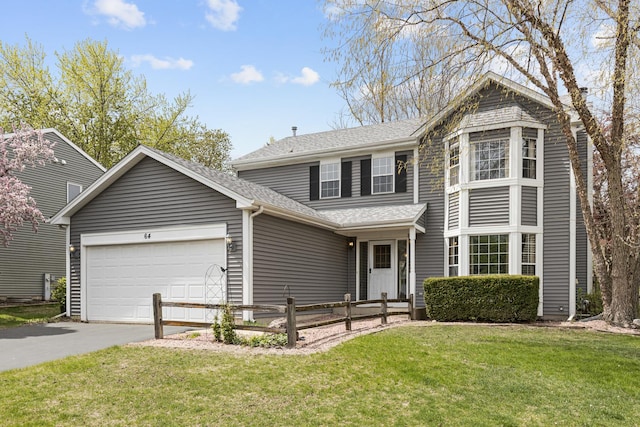 traditional-style home with an attached garage, a shingled roof, a front lawn, and aphalt driveway