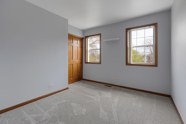carpeted spare room featuring baseboards and visible vents