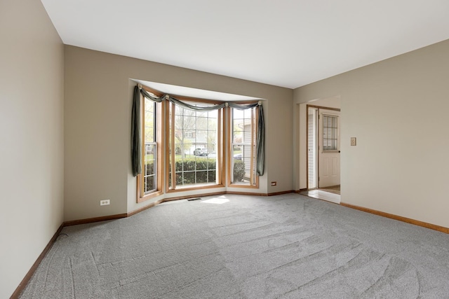 carpeted empty room featuring baseboards and visible vents