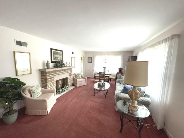 living area featuring baseboards, a stone fireplace, visible vents, and carpet floors