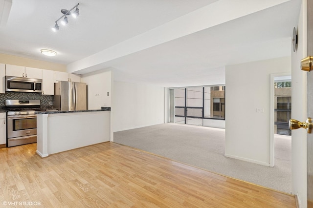 230 E Ontario St Unit 1205, Chicago, IL 60611 - kitchen featuring stainless steel appliances, dark countertops, white cabinets, light wood-style flooring, and tasteful backsplash
