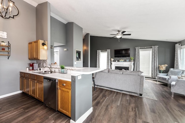 kitchen with stainless steel dishwasher, a sink, a peninsula, lofted ceiling, and open floor plan