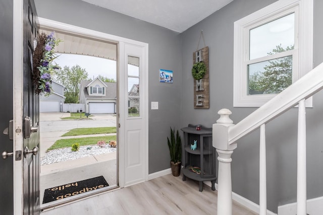 entryway featuring baseboards, stairs, and wood finished floors