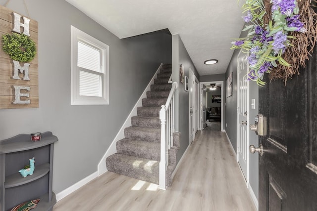 foyer with baseboards, ceiling fan, wood finished floors, and stairway