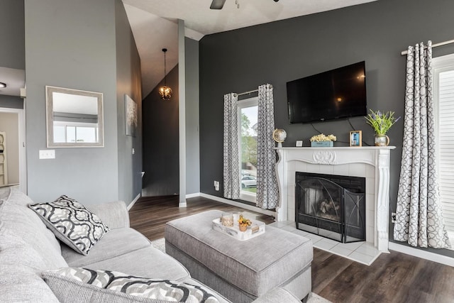 living area with baseboards, a fireplace, a ceiling fan, and wood finished floors