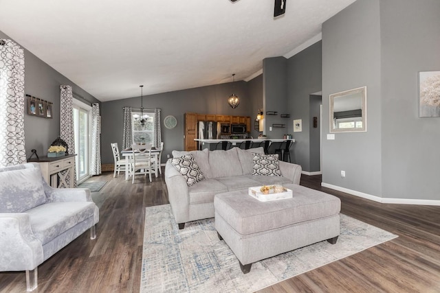 living area featuring an inviting chandelier, baseboards, vaulted ceiling, and wood finished floors