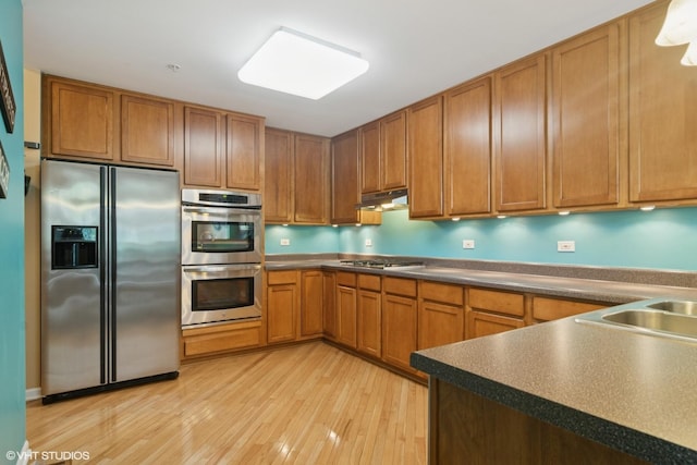 5515 Mcdonough Rd Unit 5515, Hoffman Estates, IL 60192 - kitchen with appliances with stainless steel finishes, light wood-style flooring, brown cabinetry, and under cabinet range hood