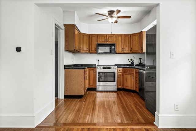 kitchen featuring ceiling fan, brown cabinetry, black microwave, stainless steel range with electric stovetop, and dishwashing machine